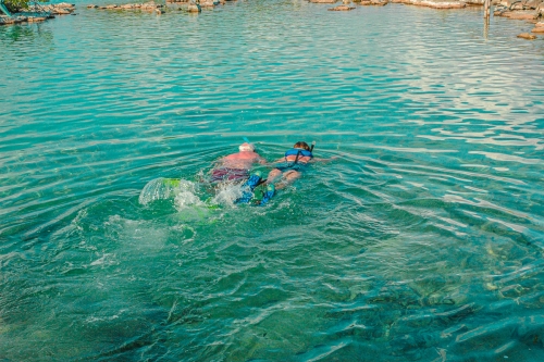 A turquoise colored lagoon with a couple of tourist snorkeling