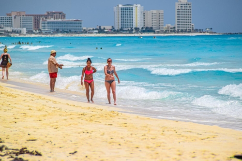 Tourists walking on the Caribbean blue waters in a Cancun Beach
