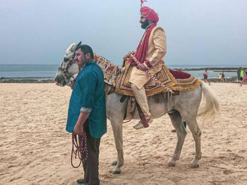 A Hindu groom on his white horse heads to his wedding