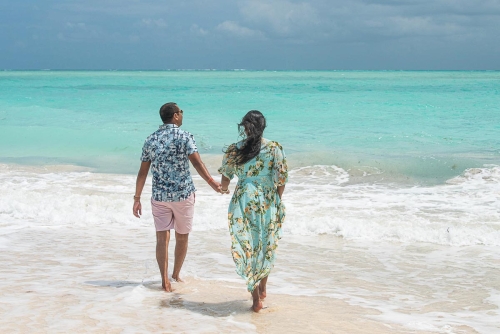 A couple of lovers walking on the beach with the Caribbean Sea in front of them